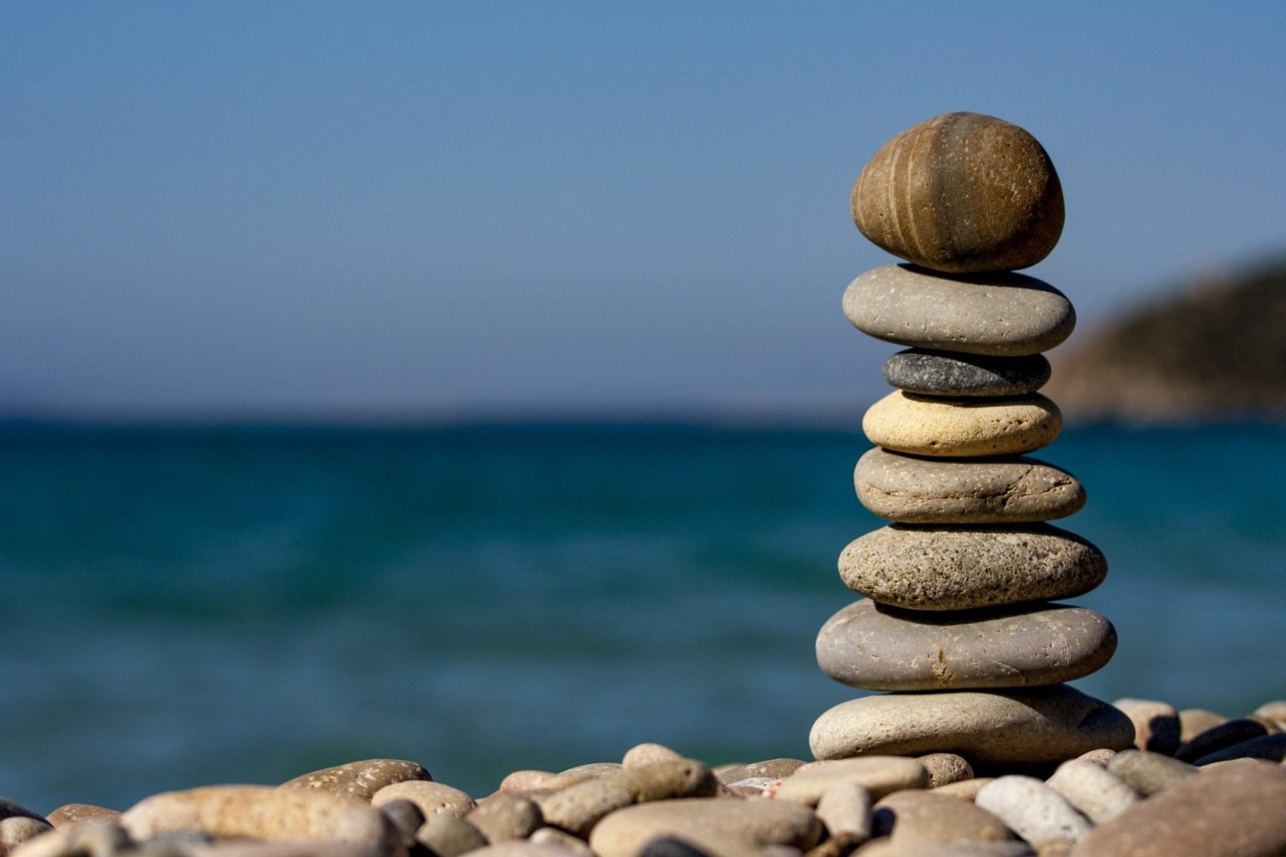 Steine balancieren sich vor einem Strand gegenseitig aus